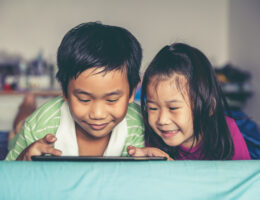Asian children watching video and playing game on digital tablet