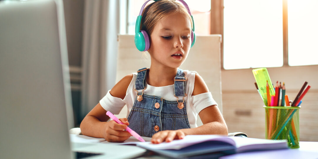 Online training. Child girl in headphones listens to a lesson on
