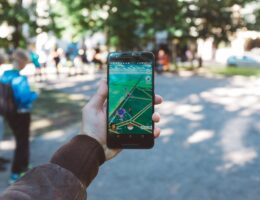 Eine Person spielt im Park Pokémon Go auf ihrem Smartphone.