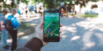 Eine Person spielt im Park Pokémon Go auf ihrem Smartphone.