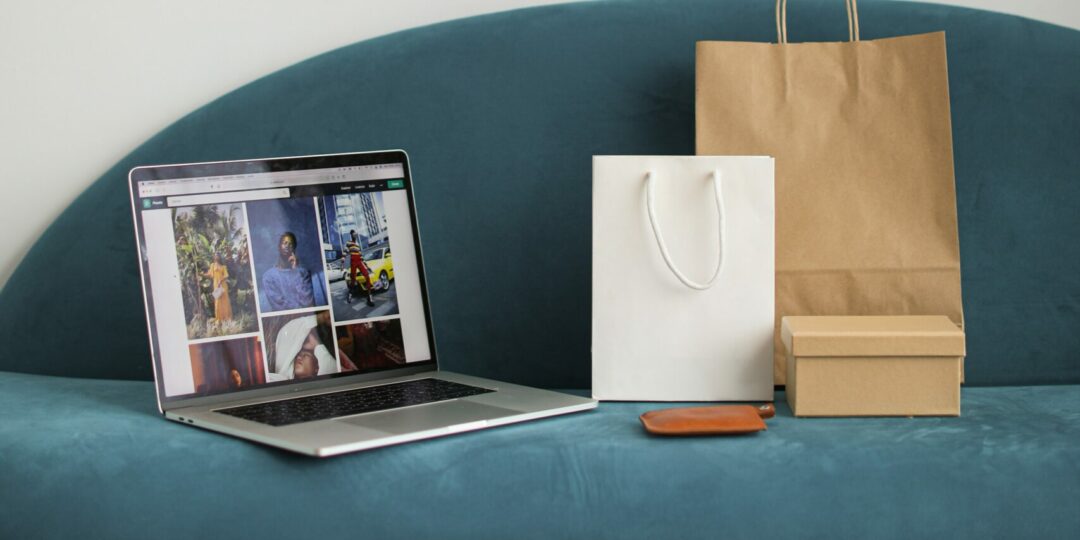 Ein Laptop und mehrere Einkaufstüten stehen auf einem Sofa.