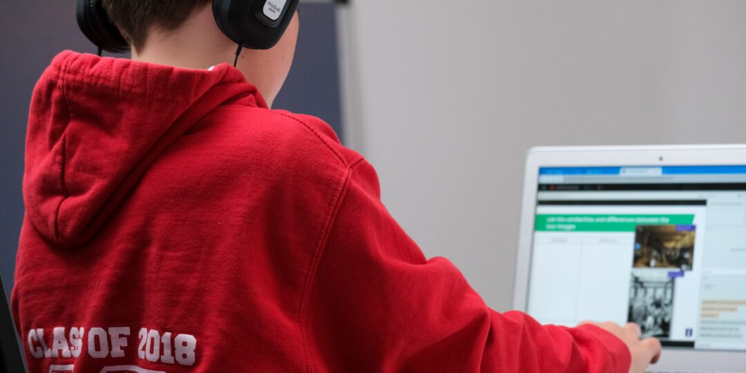 Ein Schüler sitzt mit Kopfhörern vor einem Laptop.