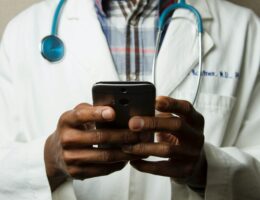 Ein Arzt mit weißem Kittel hält ein Smartphone in seinen Händen.
